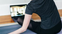 woman in black t-shirt and black pants lying on black yoga mat warm up