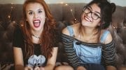 woman laughing beside woman smiling sitting on tufted sofa inside the room