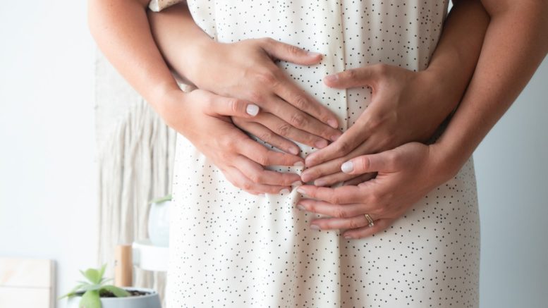 person touching person's belly symptoms of pregnancy