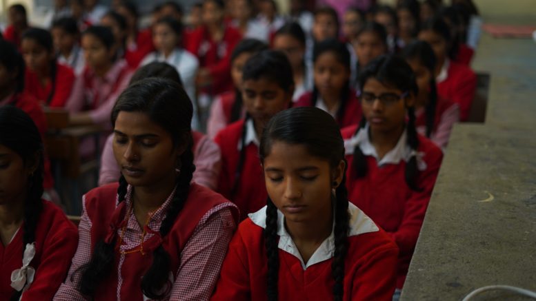 girls sitting in a classroom with eyes closed